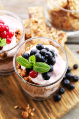 Healthy layered dessert with muesli and berries on table