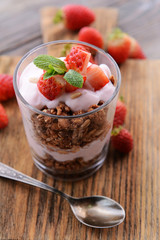 Healthy layered dessert with muesli and berries on table