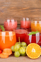 Glasses of tasty fresh juice, on wooden table.