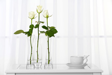 Beautiful bouquet of flowers in vases on window background