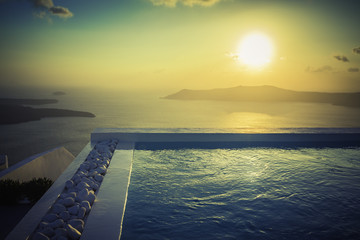 Fototapeta na wymiar Infinity pool with stones at sunset in Santorini Island, Greece