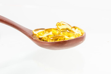 Omega 3 fish oil capsules on wooden spoon