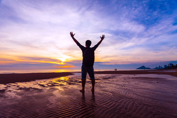 Fototapeta na wymiar Man Raising His Hands when sun rising up at sea beach