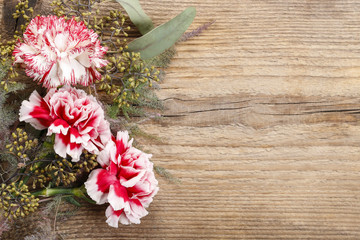 Red and white carnation flowers on wood