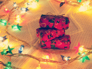 Stack of small gifts  surrounded by Christmas lights