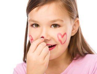 Fototapeta premium Little girl is applying lipstick on her nose