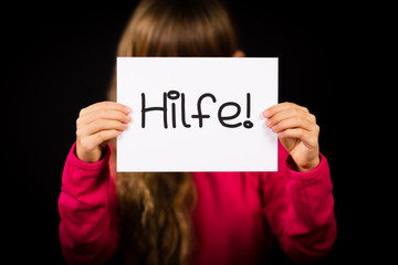 Child holding sign with German word Hilfe - Help