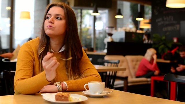 woman drinks coffee and eat cake in cafe