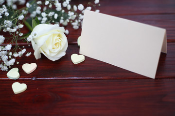 Rose, hearts and card on table