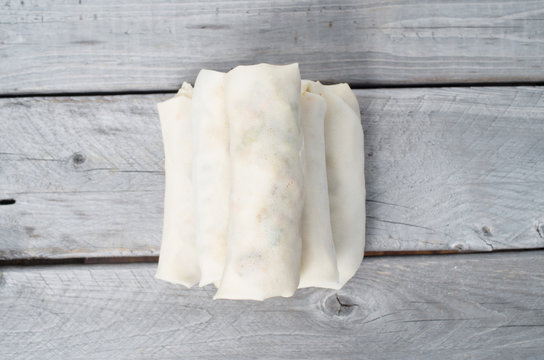 Uncooked Vietnamese egg rolls on a wooden table