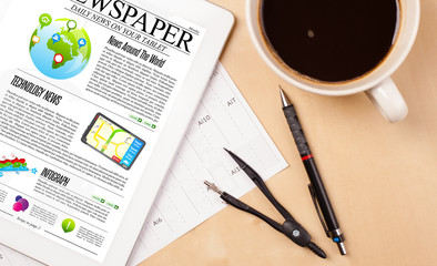 Tablet pc shows news on screen with a cup of coffee on a desk