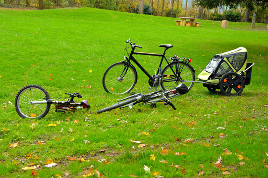 Bicycles and a trailer parked on a lawn at a picknic area.