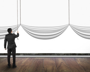 businessman pulling open blank curtain with empty white backgrou