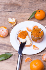 slice of bread with butter and tangerine jam on white plate.