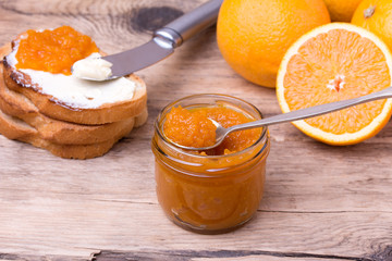 slices of bread with butter and orange jam on wooden desk