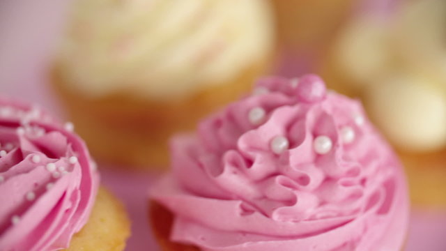 Closeup pan of beautifully decorated pink and white cupcakes