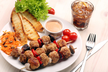 Minced meatballs baked as skewers with carrot salad on white pla