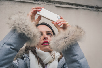 Beautiful young brunette taking a picture in the city streets