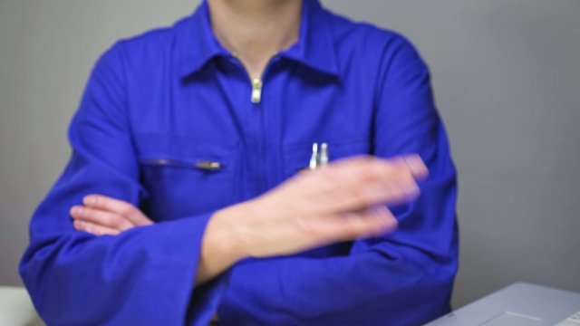 woman in blue work uniform making the Okay sign