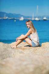 Beautiful young girl sitting on a rock