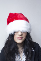 Girl hiding her face with santa hat