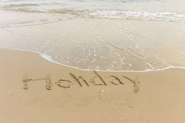 Holiday word written in the sandy beach