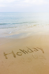 Holiday word written in the sandy beach