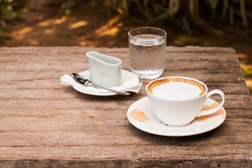 Cup of hot cappuccino coffee on wooden table.