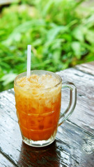Milk tea with ice on wooden table (Thai beverage)