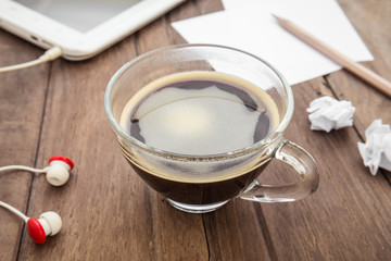 Cup of coffee, tablet and paper on table
