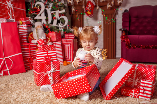 beautiful little girl with gifts near a Christmas tree