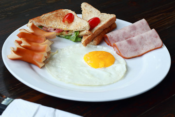 Eggs  ham and  hot dog on dishware.