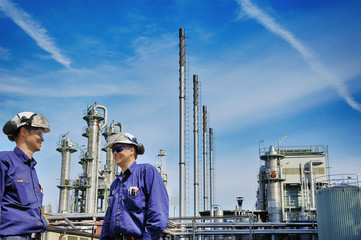 oil workers in front of large chemical refinery