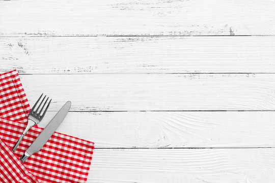 knife and fork on white old vintage wooden table with red checke
