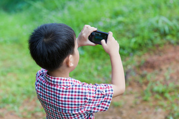 Little boy taking photos by digital camera on smartphone with go