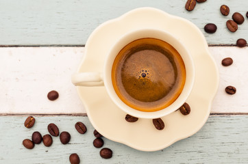 Coffee cup and beans on wooden table background with vintage fil