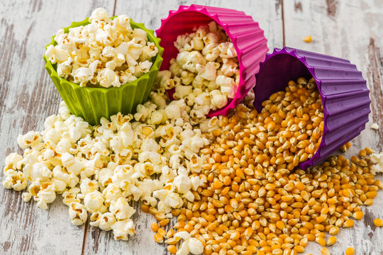 Pile of Popcorn in Colorful Bowls on White Wooden Background