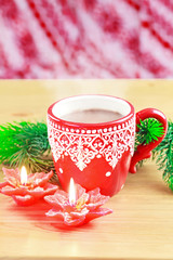 Cup of hot cocao with red poinsettia candle and pine