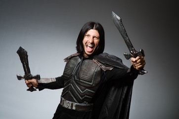 Angry knight with sword against dark background