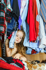 Cute little girl hiding inside wardrobe from her parents