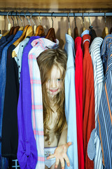 Cute little girl hiding inside wardrobe from her parents
