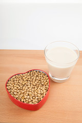 Soy milk in glass with soybeans in heart shape box