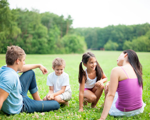 Fototapeta premium Junge glückliche Familie sitzt im Sommer im Gras