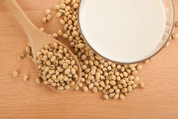 Soy milk in glass with soybeans and wooden spoon