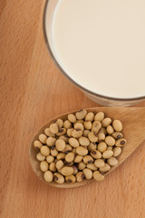 Soy milk in glass with soybeans and wooden spoon