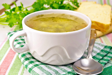 Soup of green peas with bread on tablecloth