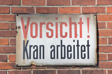 Vorsicht Kran arbeitet retro sign on brick wall