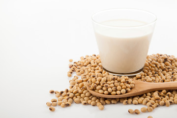 Soy milk in glass with soybeans and wooden spoon