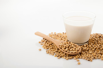 Soy milk in glass with soybeans and wooden spoon