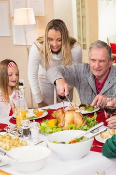 Grandfather carving chicken during christmas dinner